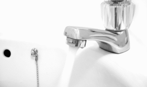 Why should you occasionally run all taps, even in rarely used bathrooms or utility areas?